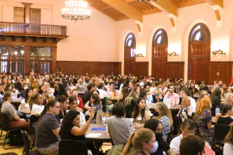 Ballroom with students working in groups at round tables. 