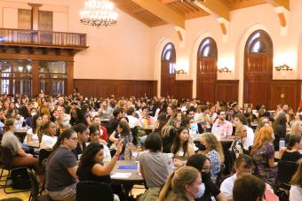 Ballroom with students working in groups at round tables. 