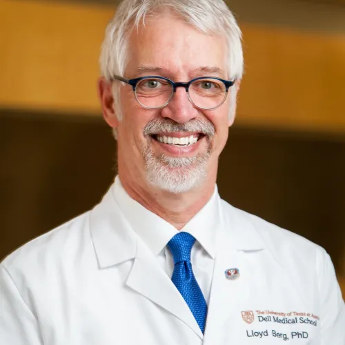 Man in glasses in a white medical coat and a blue tie smiling 