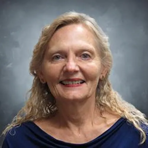 Woman with long blonde hair and a blue top smiling