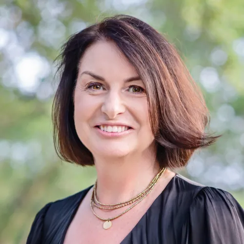 Tina Mowday headshot Woman with short brown hair and a black blous smiling