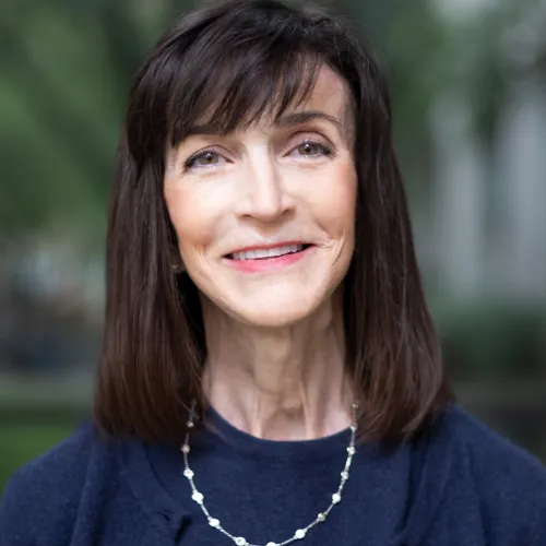 Woman with dark, shoulder-length hair and a navy top smiling warmly. 