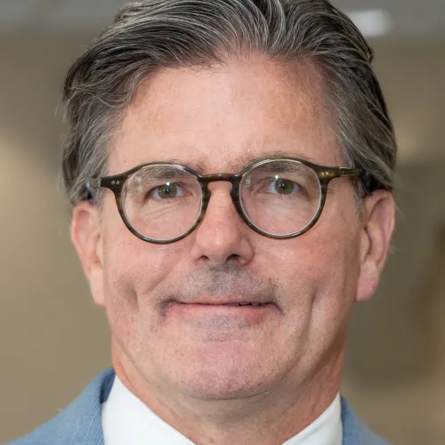Man wearing round glasses smiling. 
